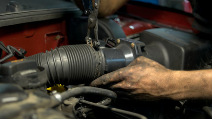 Fototapeta na wymiar Close up worker installing car engine hose. Mechanic assembling car mechanism.