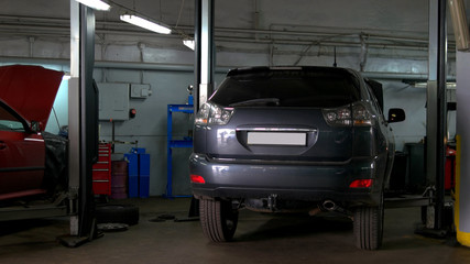 Two cars with an opened hood in car repair service. One car is lexus rx and another is Skoda Octavia. Back view of cars.