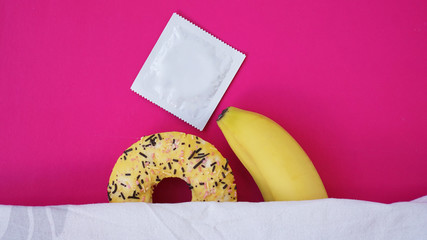 Sweet donut and banana on pink color background. Sex and Erotic concept. Banana hugs donut in bed....