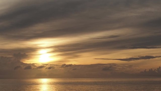 Golden sunrise over ocean, soft light clouds