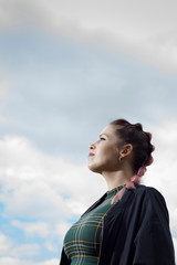 Woman looking at the sky in profile in the field in spring, with her hair up