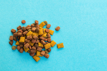 Heap of colorful dry cat food on a blue background