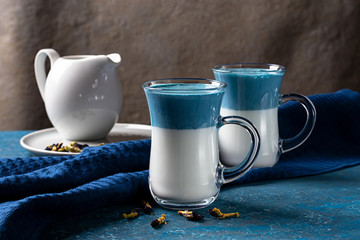 2 cups blue latte matcha, cream drink from pea butterflies on a blue background. Horizontal...