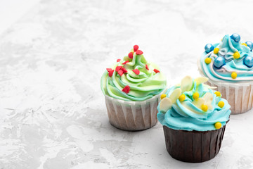Colorful cupcakes decorated by caramel candies on grey table. Horizontal with space for text