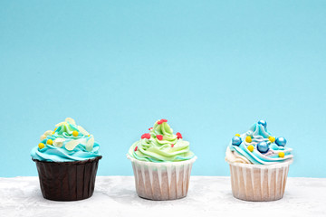Colorful cupcakes decorated by caramel candies on blue background. Horizontal with space for text