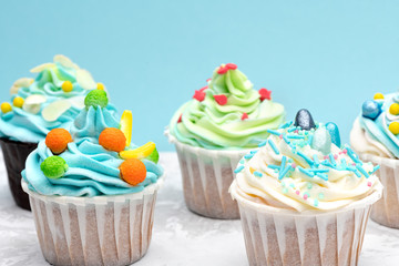 Colorful cupcakes decorated by caramel candies on blue background. Horizontal with space for text