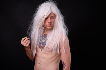 Punk rocker man wearing wig against black background