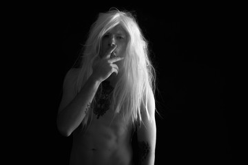 Punk rocker man wearing wig against black background in black and white