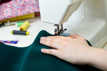Teenager, boy learns to sew on a sewing machine at home, hands close-up. Concept - hobbies - unisex, training, new skills