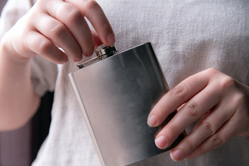 Hand holding a stainless steel hip flask for liquor, alcohol and drink concept close-up