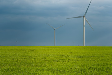 Landscape view of wind power turbine among green meadow with sky in the morning and copy space for text in the sky. Green energy concept.