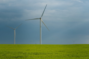 Landscape view of wind power turbine among green meadow with sky in the morning and copy space for text in the sky. Green energy concept.