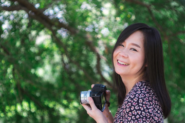 Portrait of beautiful smiling asian woman with holding camera at summer green park