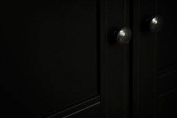 closeup of metallic door knob on black clothes cabinet