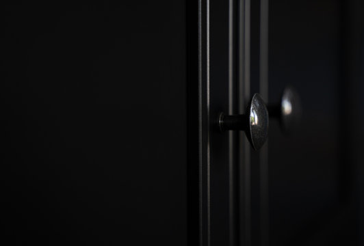 closeup of metallic door knob on black clothes cabinet