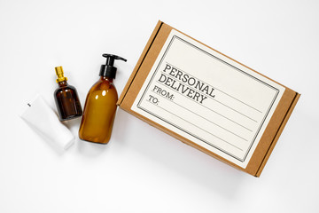 The cardboard box with label written about personal delivery and some cosmetic treatment bottles, on white background with copy space for any text. Post or courier service concept