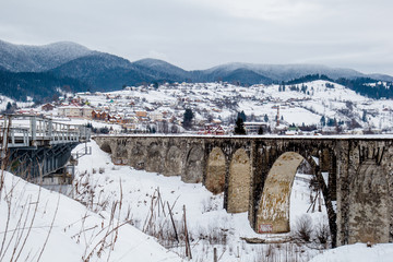 Winter mountains background with viaduct bridge and village. Winter landscape