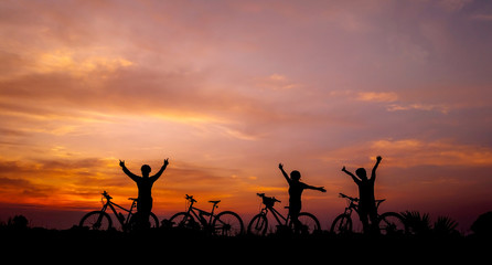 Fototapeta na wymiar Family cyclist and Bicycle silhouettes on the dark background of sunsets