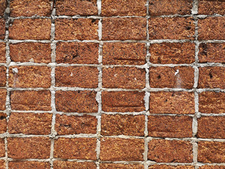 Red stone wall stacked up grout with grey cement Rock porous rough surface material texture background