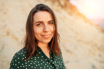 A face of beautiful woman in sunset light. Young brunette woman with a green eyes is looking at the camera