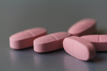Obraz na płótnie Canvas Long pink pills on the silver background. Selective focus, shallow depth of field