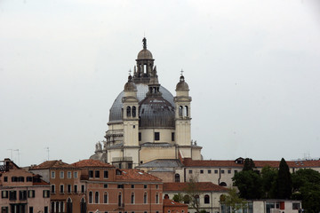 Fototapeta na wymiar Cityscape with Santa Maria della Salute church, historical facades in Venice. View from the adriatic sea