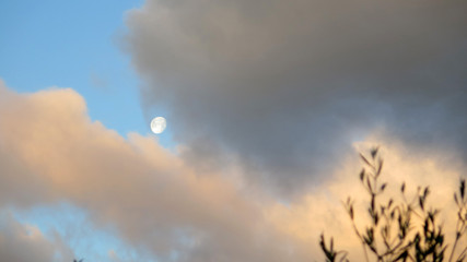 Coloreed rainclouds nearly obscuring daytime moon