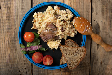 Serving of tourist food. Fried eggs with meat and vegetables.