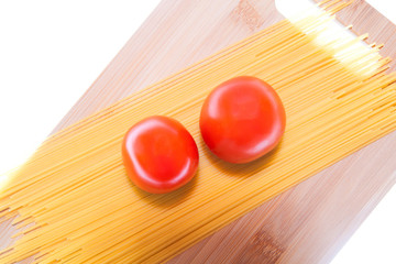 Tomatoes, spaghetti and cutting board on a white background