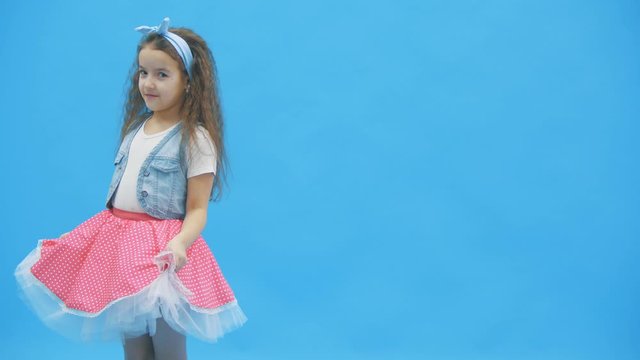 LIttle girl standing over blue background in 4k video.