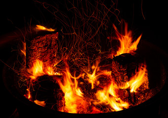 Burning firewood with sparks close-up in the dark