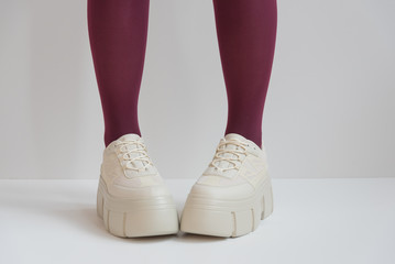 long slender legs close-up. Thick-soled sneakers. Red stockings or tights. Trend, fashion, trend