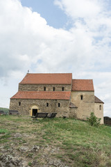 Fototapeta premium Cisnadioara, Transylvania, Romania. Fortified medieval church on top of rock hill in Cisnadioara near Sibiu, Transylvania, Romania. Cloudy summer day.