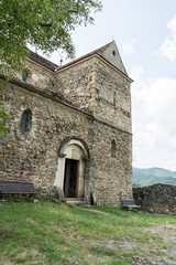 Fototapeta na wymiar Cisnadioara, Transylvania, Romania. Fortified medieval church on top of rock hill in Cisnadioara near Sibiu, Transylvania, Romania. Cloudy summer day.