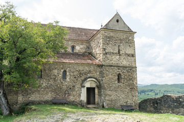 Fototapeta premium Cisnadioara, Transylvania, Romania. Fortified medieval church on top of rock hill in Cisnadioara near Sibiu, Transylvania, Romania. Cloudy summer day.