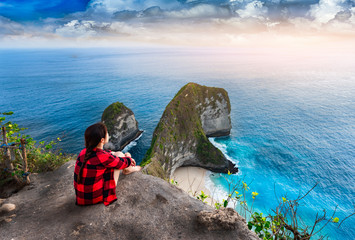 Girl sitting on a cliff and enjoys the view to trex mountain on nusa penida island in bali ,Indonesia. © chanchai