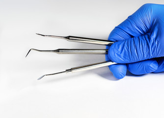Sterile instruments in the dentist's hand in blue disposable latex gloves .