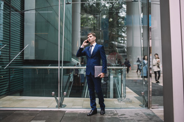 Businessman talking on phone near office building