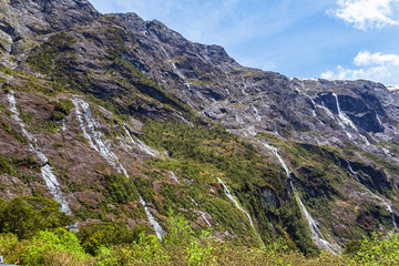Fototapeta na wymiar Small waterfalls and streams from sheer cliffs on the way to Fiordland. South Island, New Zealand