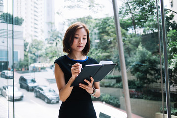 Thoughtful Asian female secretary taking notes