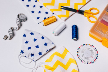 Personal protection mask, cloth, scissors, thread and a centimeter are on a white background