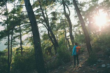 A girl with a backpack goes along a mountain trail.