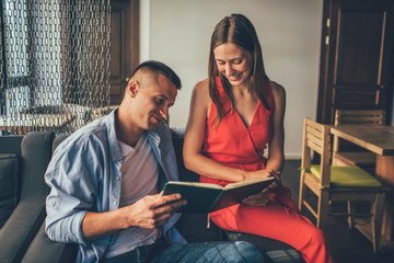 Smiling couple reading book together at home