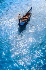 Fototapeta premium Gondola with tourists and a gondolier on the canal in Venice. Gondolier carries tourists on gondola Grand Canal of Venice, Italy.