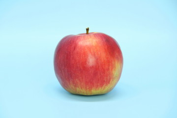 Red yellow apple on a blue background. Juicy ripe beautiful fruit.
