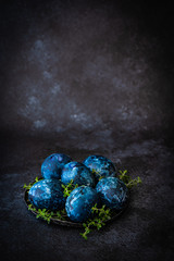 Easter eggs painted by hand in blue color on dark background. Chicken and quail eggs catholic and orthodox easter holiday