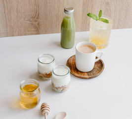 Healthy breakfast set with coffee, homemade yogurts with granola, honey or agave syrup and green juice. 