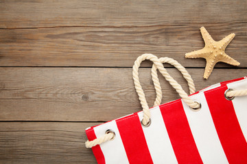 Red summer bag with seashells on grey wooden background