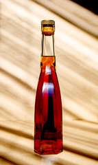 glass bottle of brandy, cognac on a background with slanting shadows