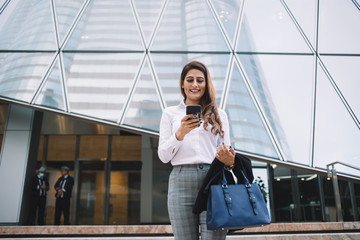 Joyful employee reading messages on smartphone